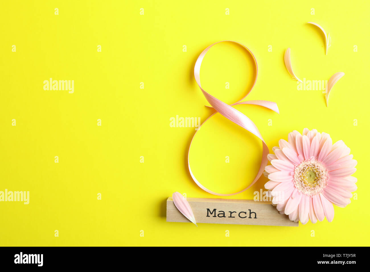 8 March, International Women's Day. Figure eight of pink ribbon with beautiful gerbera on yellow background. Space for text Stock Photo