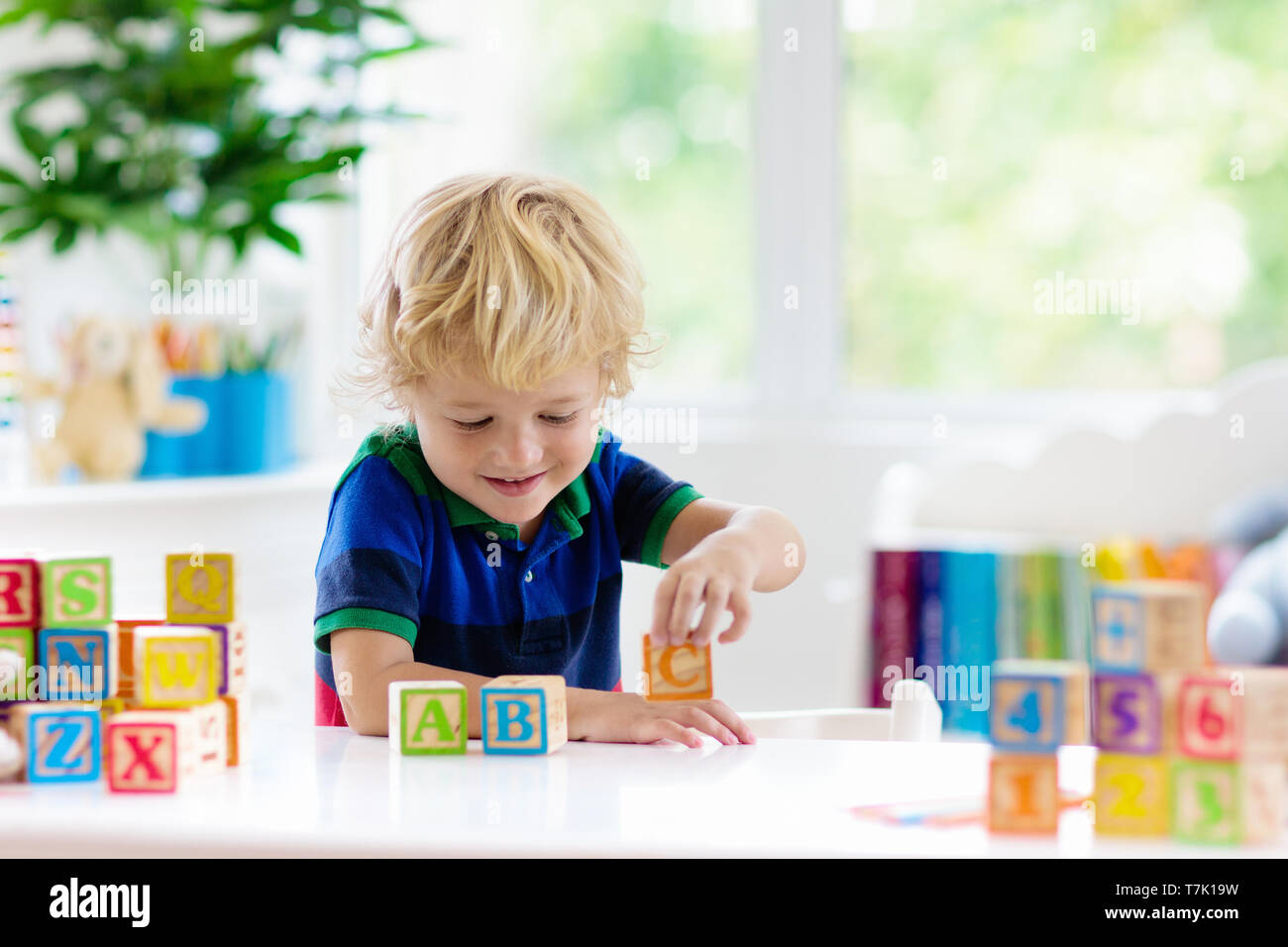 Child learning letters and numbers. Kid with colorful wooden abc blocks