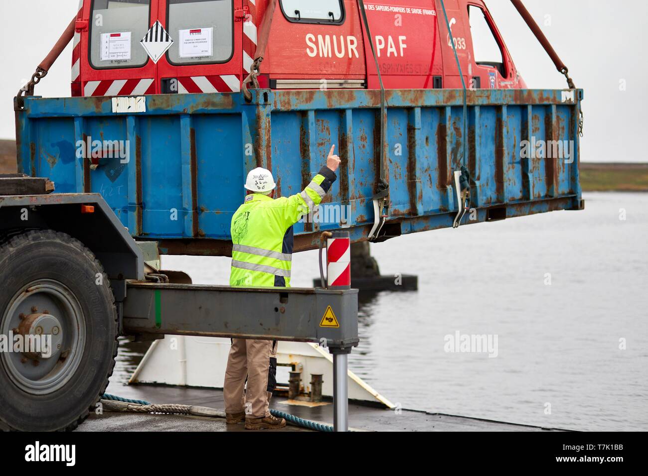 France, French Southern and Antarctic Territories (TAAF), Kerguelen Islands, Port-aux-Français, loading a old rescue vehicle on the barge Aventure II. The container will be take off on board the Marion Dufresne (supply ship of French Southern and Antarctic Territories) Stock Photo