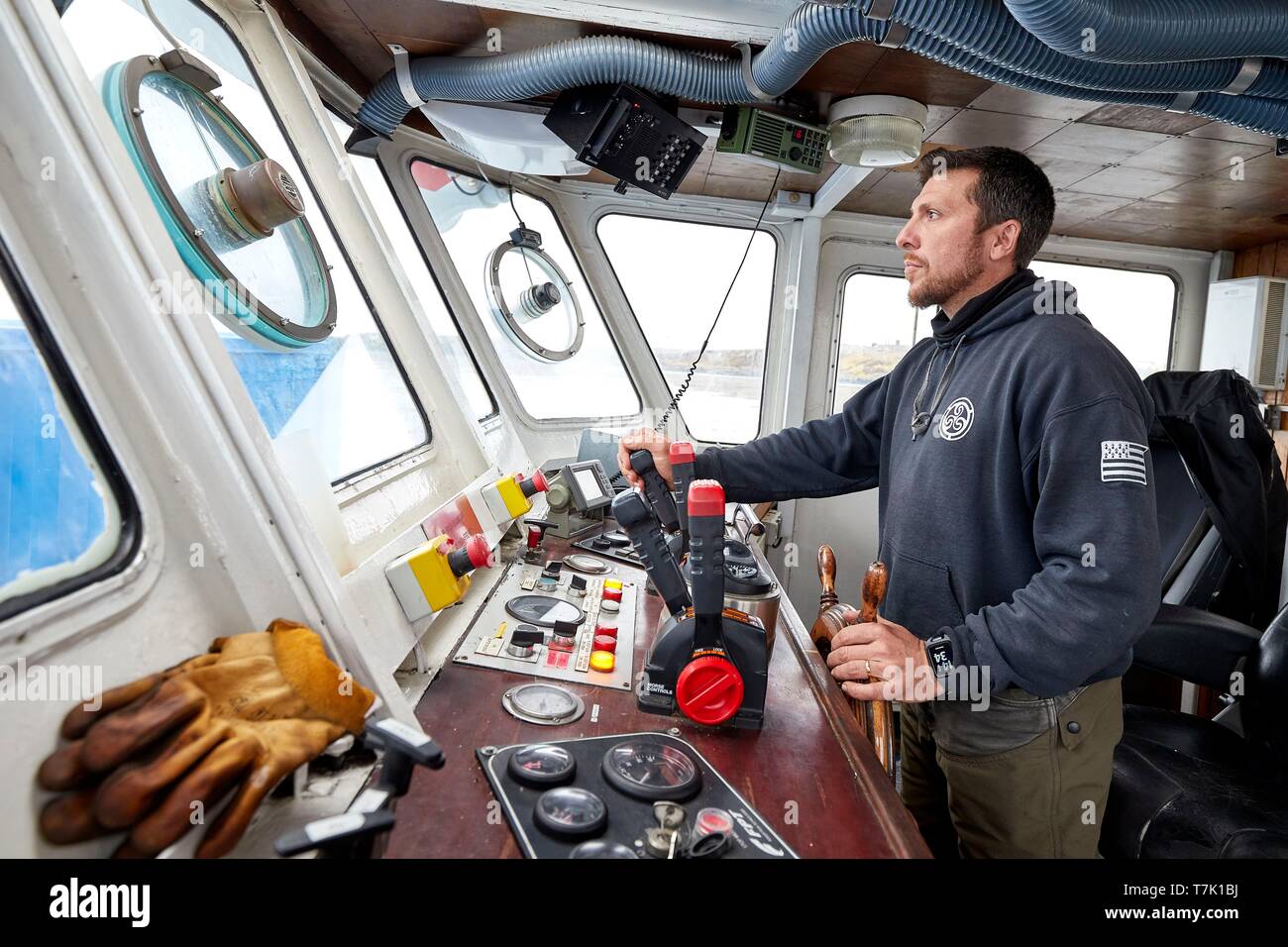 France, French Southern and Antarctic Territories (TAAF), Kerguelen Islands, Port-aux-Français, the captain at the wheel of the barge Aventure II, the only boat of the island. The boat transports the heavy freight (container) between the Marion Dufresne and the pier of Port-aux-Français Stock Photo