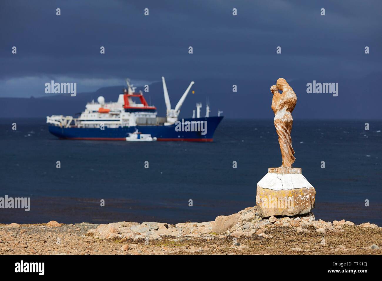 France, French Southern and Antarctic Territories (TAAF), Kerguelen Islands, Port-aux-Français, statue of Notre-Dame-des Vents on the coast in front of the Marion Dufresne (supply ship of French Southern and Antarctic Territories) at anchor Stock Photo