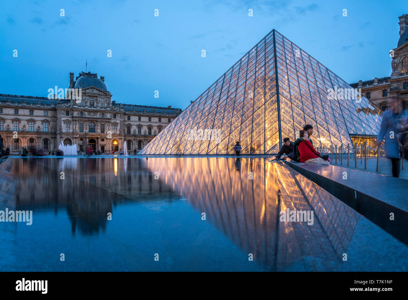 Palais du Louvre, Brunnen und Glaspyramide in Abenddämmerung, Paris, Frankreich  |  Louvre Palace, fountain and glass pyramid at dusk, Paris, France Stock Photo