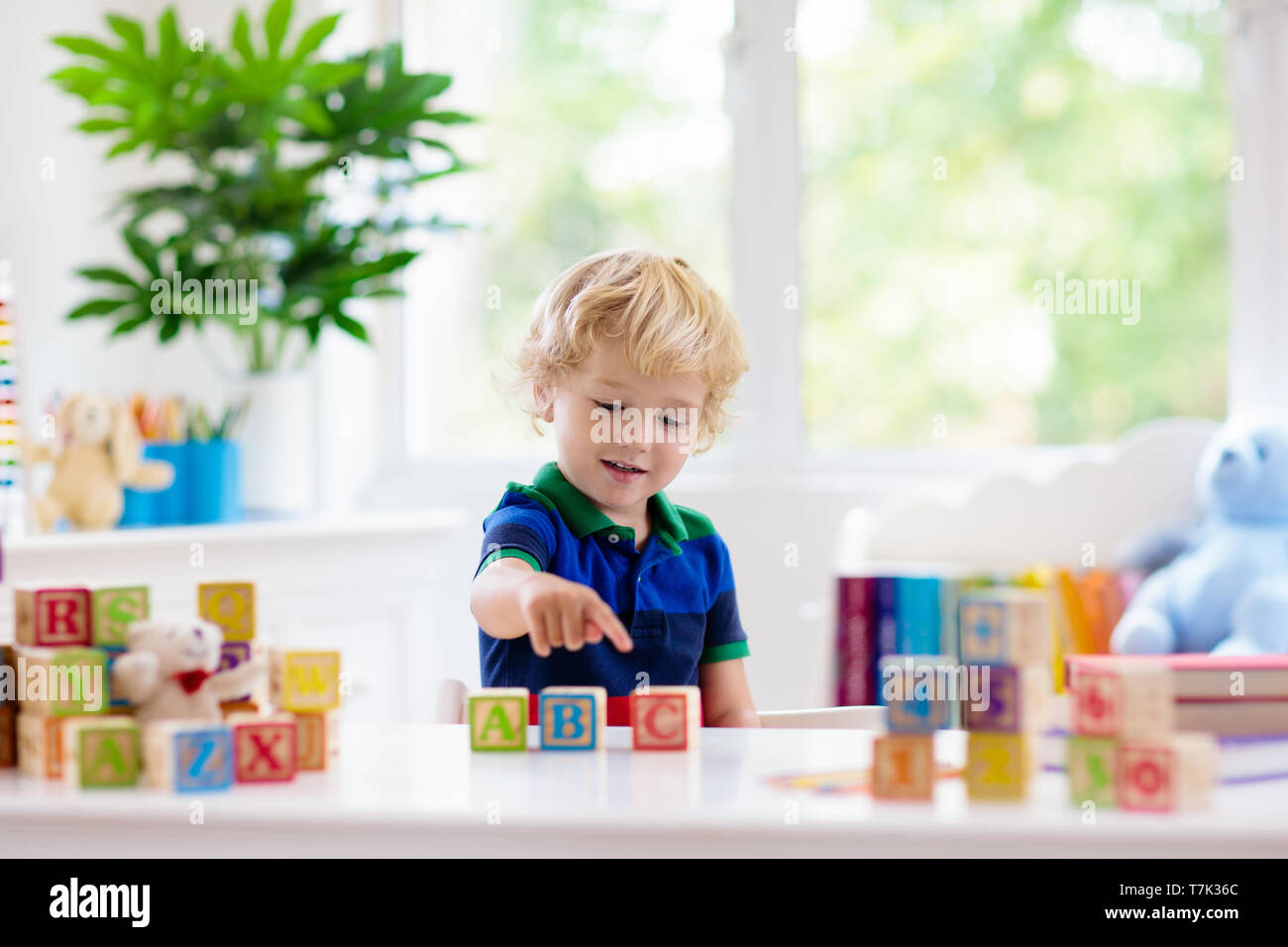 Child learning letters and numbers. Kid with colorful wooden abc blocks