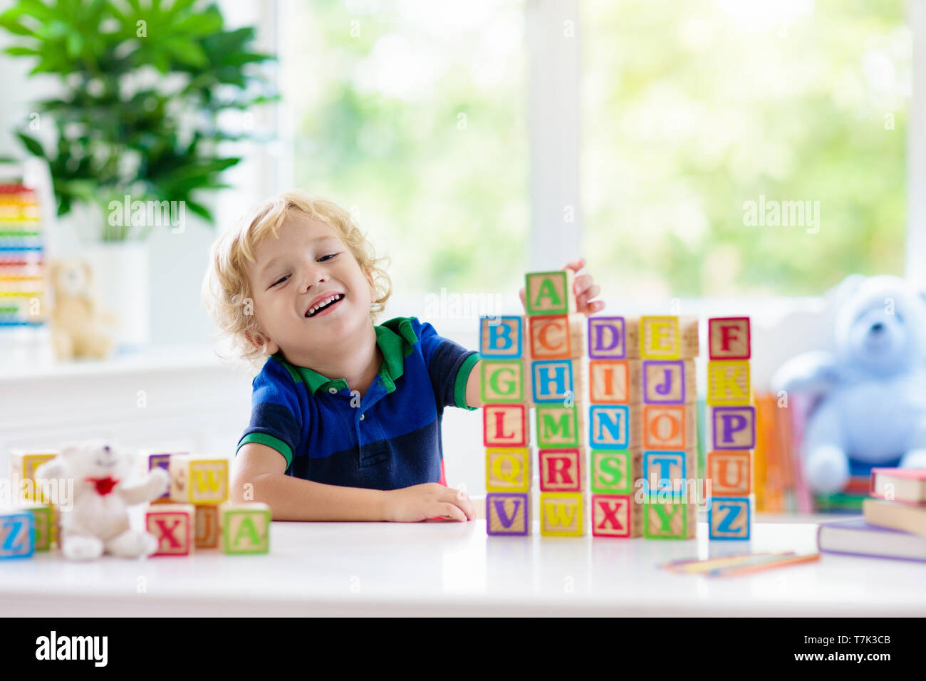 Child learning letters and numbers. Kid with colorful wooden abc blocks