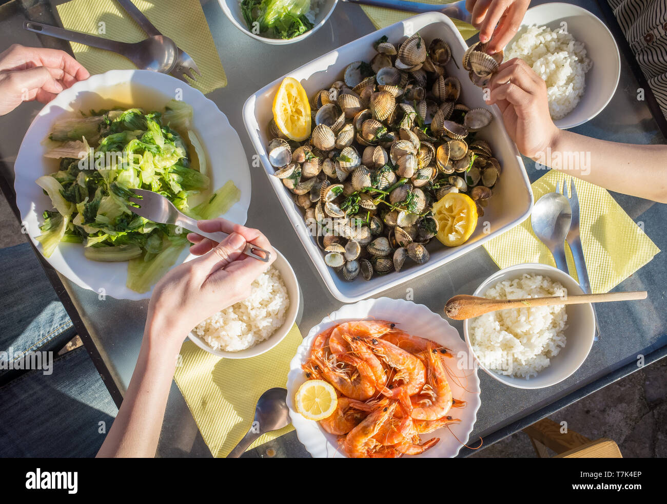 A few people are enjoying a seafood meal with some vegatables and rice