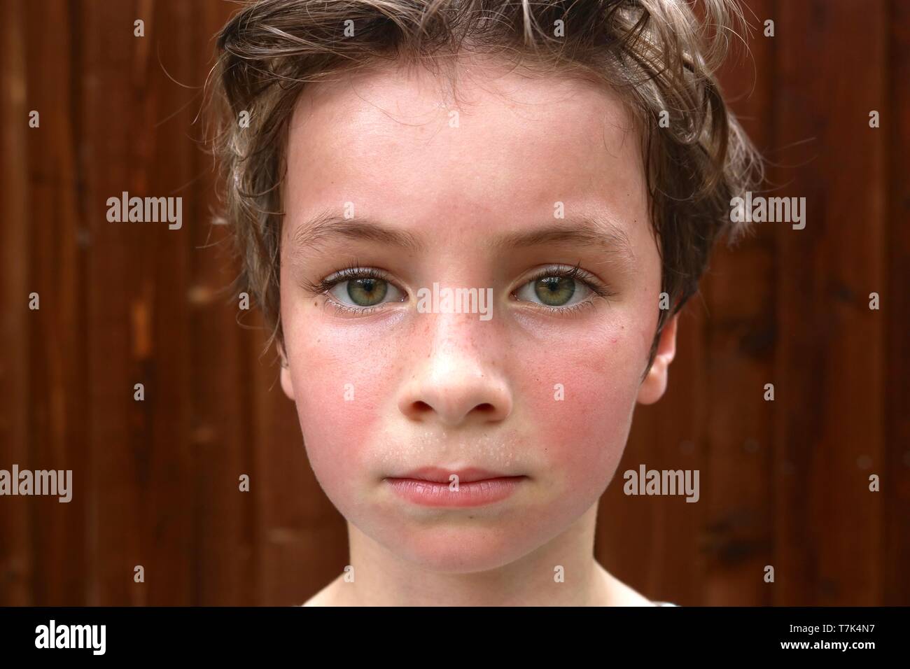 Portrait of a hot and sweaty child with big green eyes and short brown hair Stock Photo