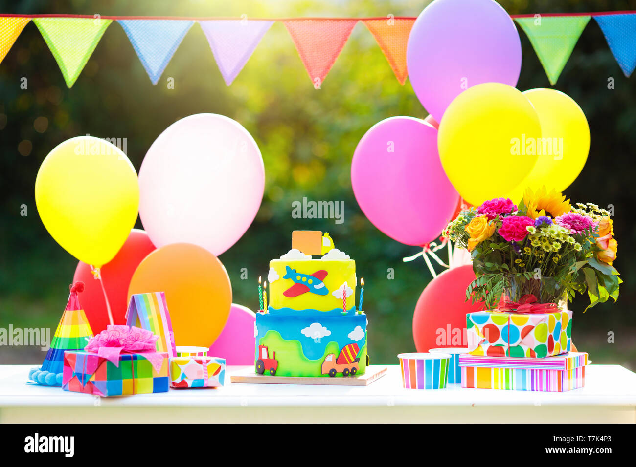 Kids birthday party decoration. Colorful cake with candles. Car and transportation theme boys party. Decorated table for child birthday celebration. R Stock Photo