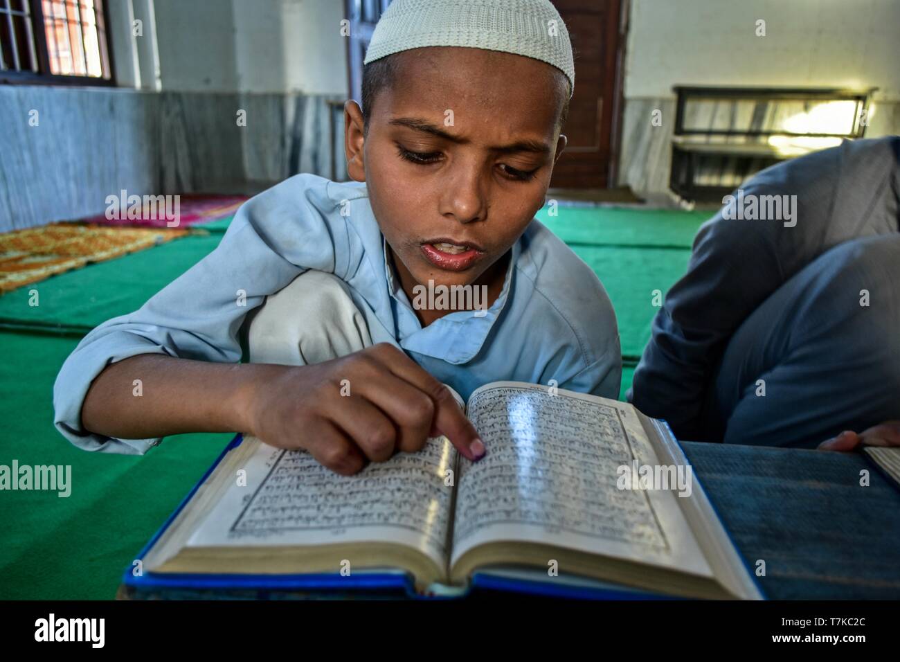 An Indian Muslim boy seen reciting the holy Quran in a mosque during the first day of the holy fasting month of Ramadan in Patiala district of Punjab. Muslims throughout the world are marking the month of Ramadan, the holiest month in the Islamic calendar in which devotees fast from dawn till dusk. Stock Photo