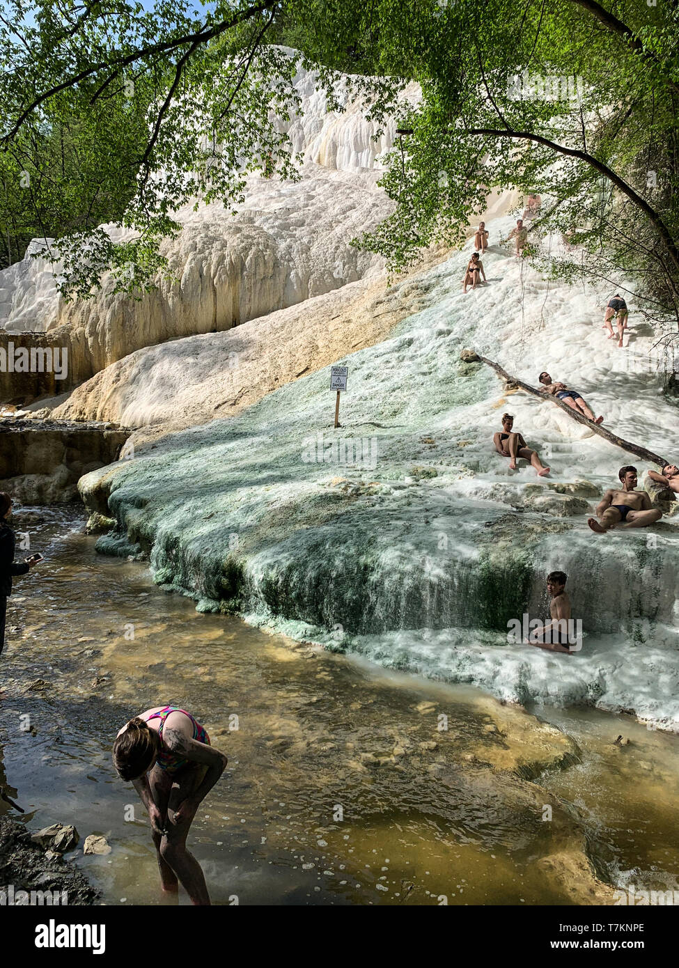 Bagni San Filippo, Italy - April 24, 2019: People rest on the thermal salt waterfalls of the mineral springs of Bagni San Filippo on a sunny day. Stock Photo