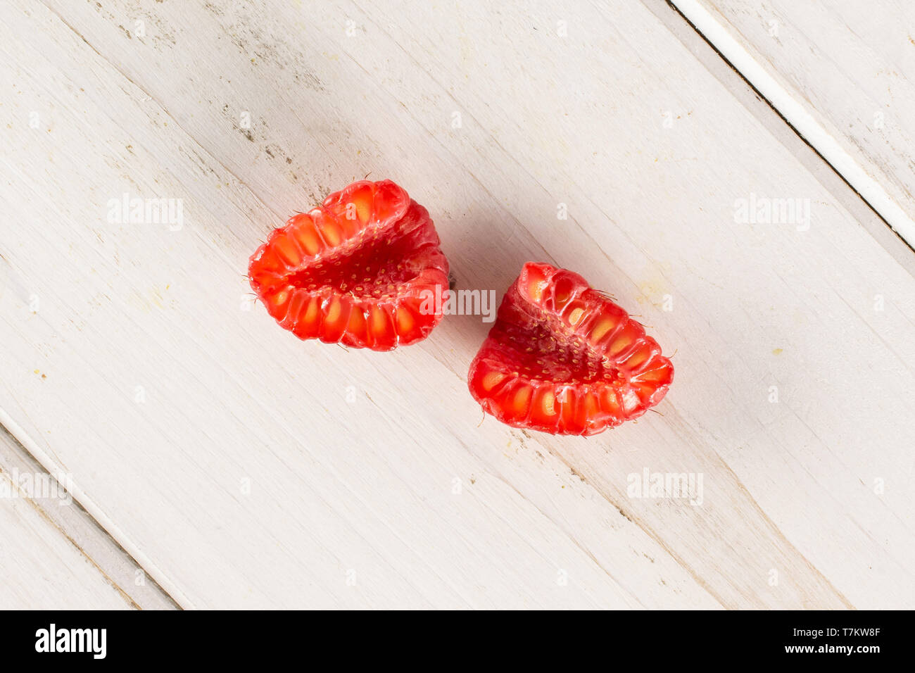 Group of two halves of fresh red raspberry cross section flatlay on white wood Stock Photo