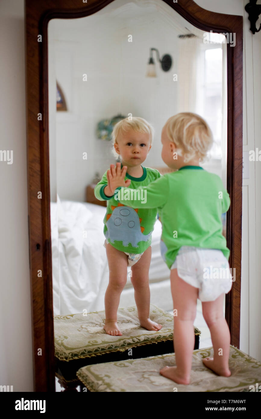 Portrait of a young toddler in nappies looking at his reflection in a  bedroom mirror Stock Photo - Alamy, image size:866x1390