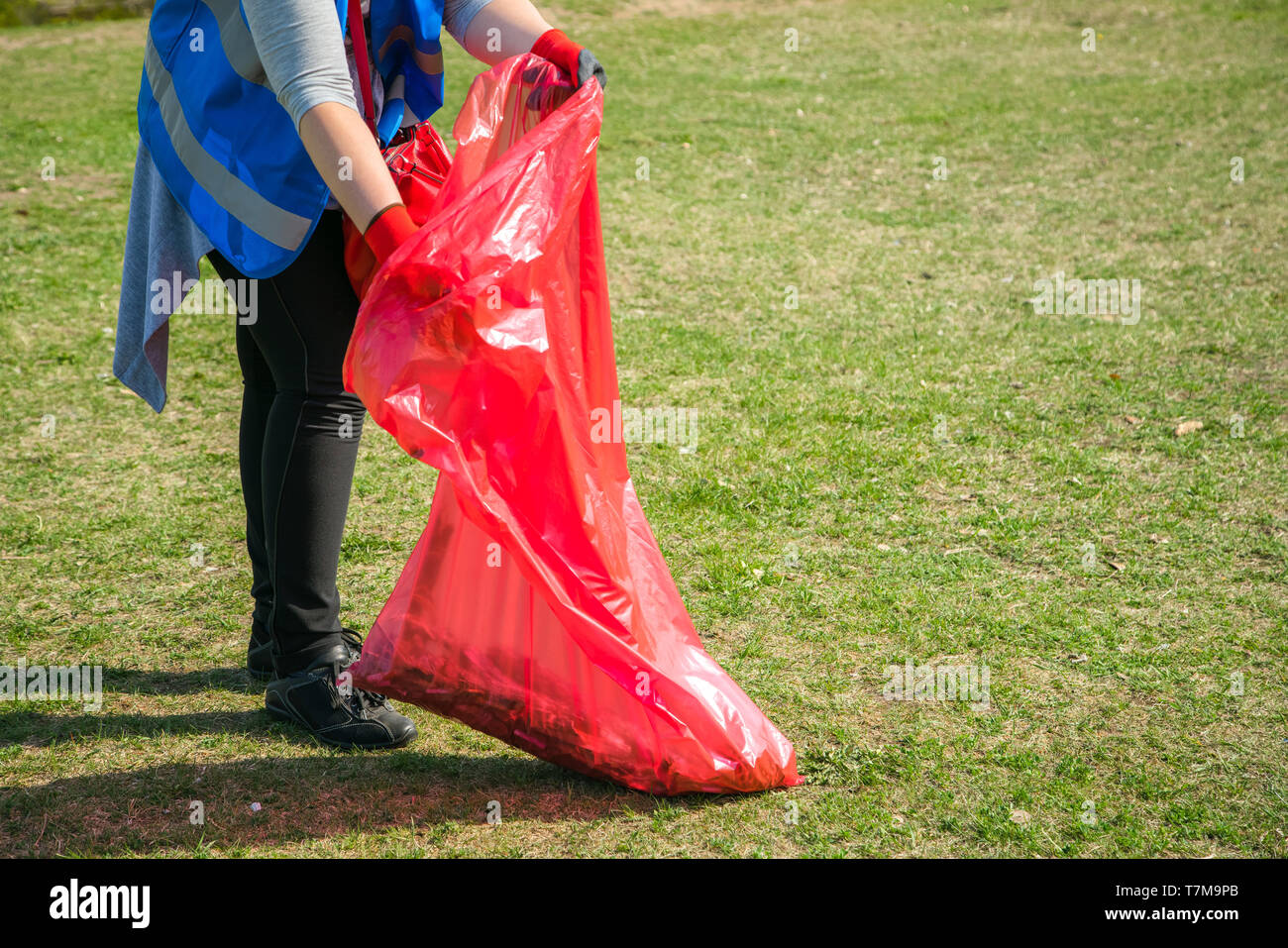 Woman volunteer wearing picking up trash and plastic waste in public