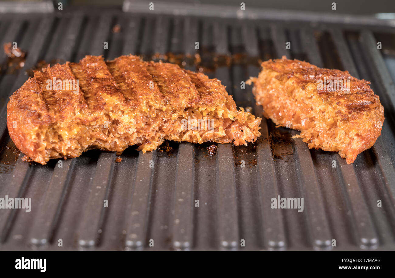 Close up of plant based burger patties on griddle being grilled Stock
