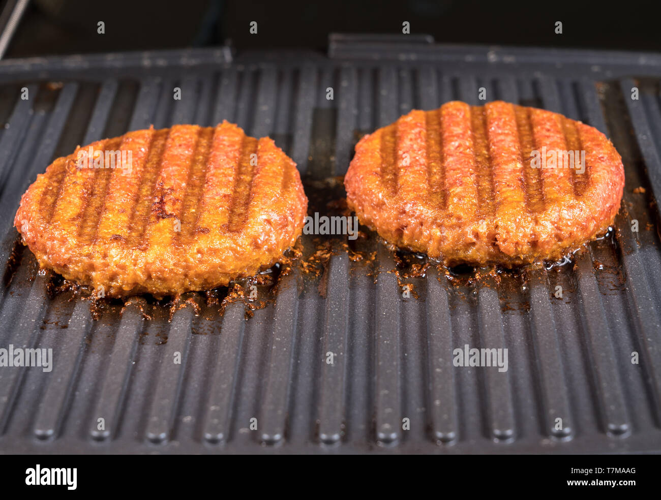 Close up of plant based burger patties on griddle being grilled Stock
