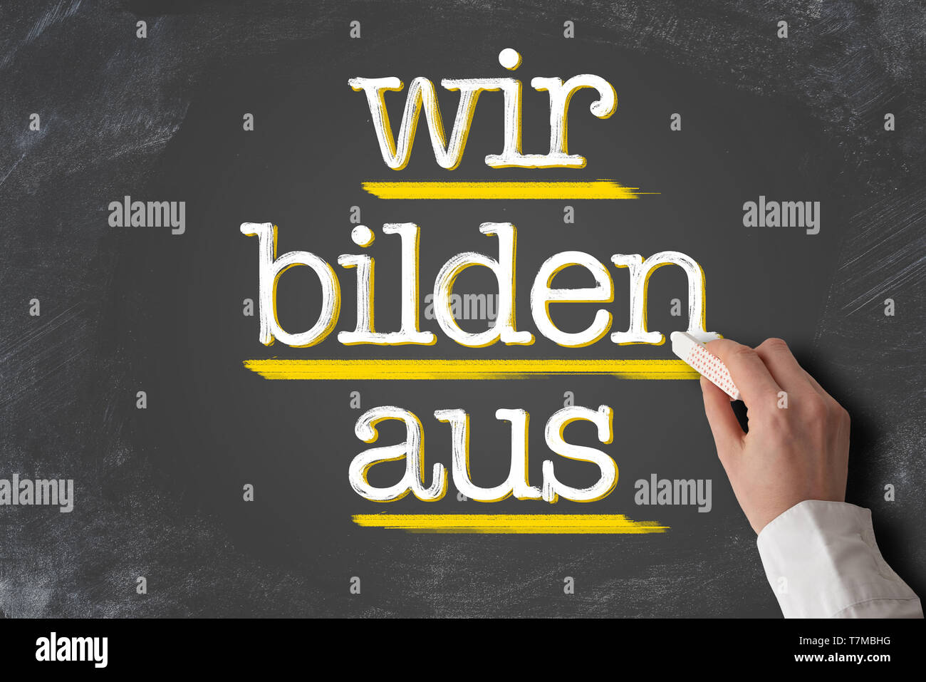 text WIR BILDEN AUS, German for we train apprentices, written on blackboard Stock Photo