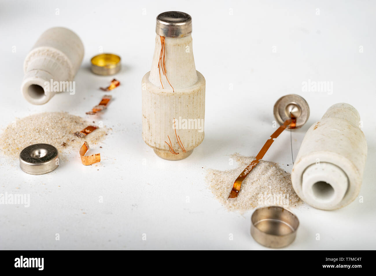 Old ceramic electric fuse. Blown and badly repaired security for energy, Bright background Stock