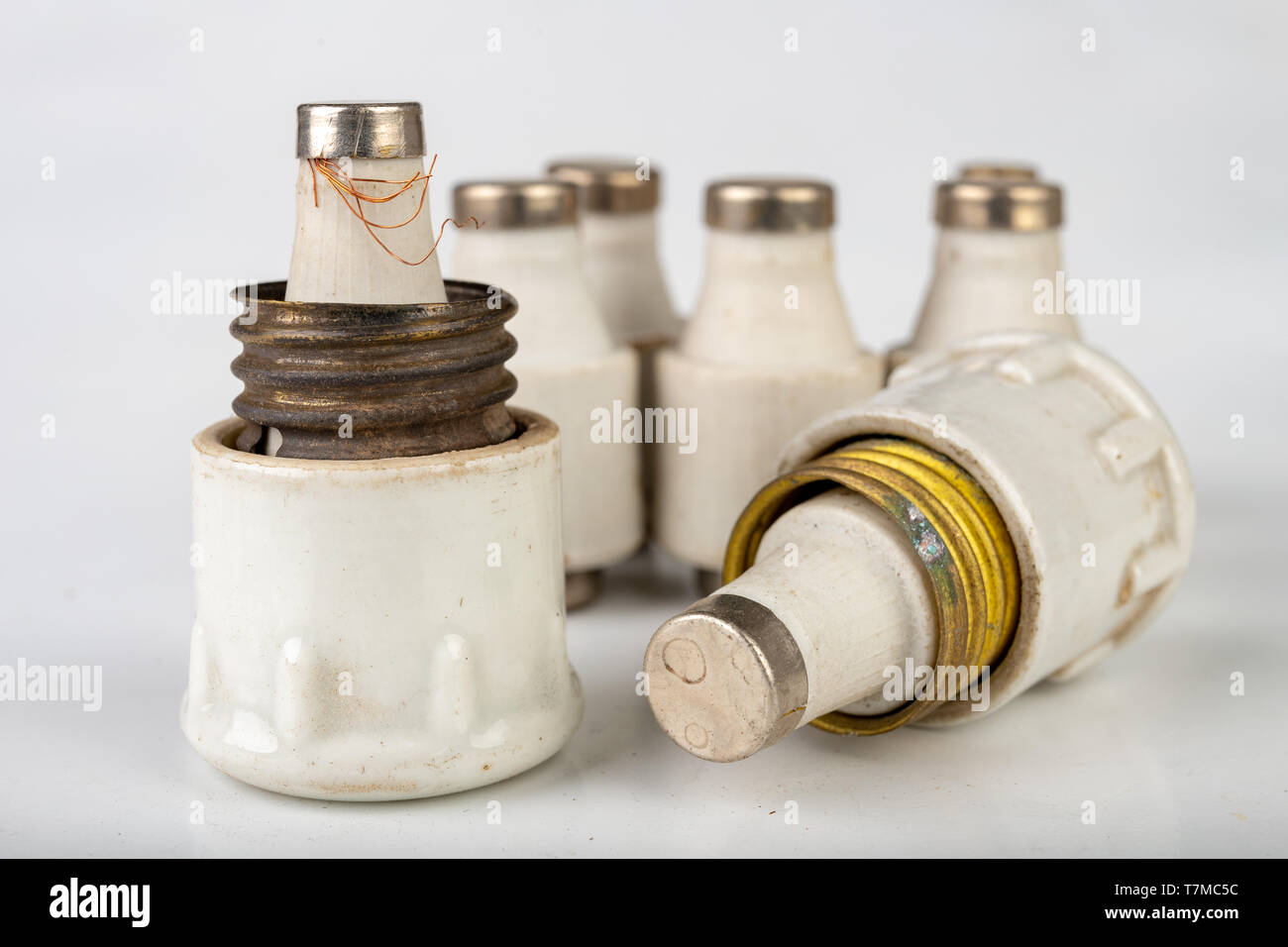 Old ceramic electric fuse. Blown and badly repaired security for energy, Bright background Stock