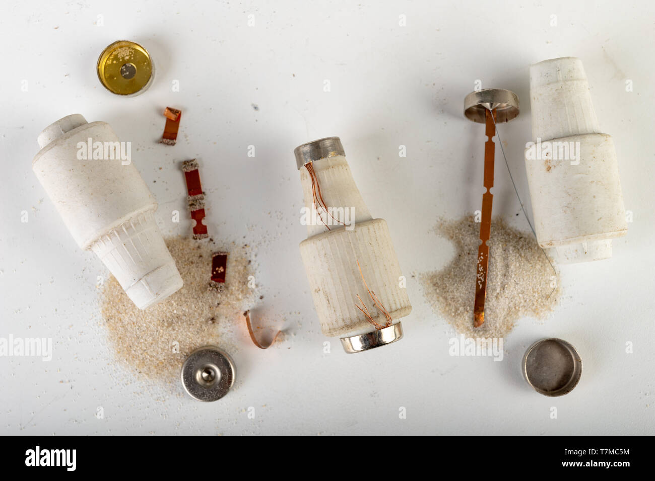 Old ceramic electric fuse. Blown and badly repaired security for energy, Bright background Stock
