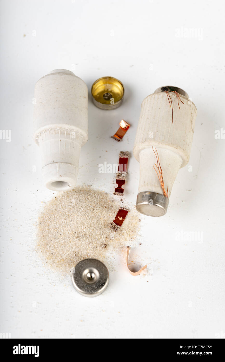 Old ceramic electric fuse. Blown and badly repaired security for energy, Bright background Stock