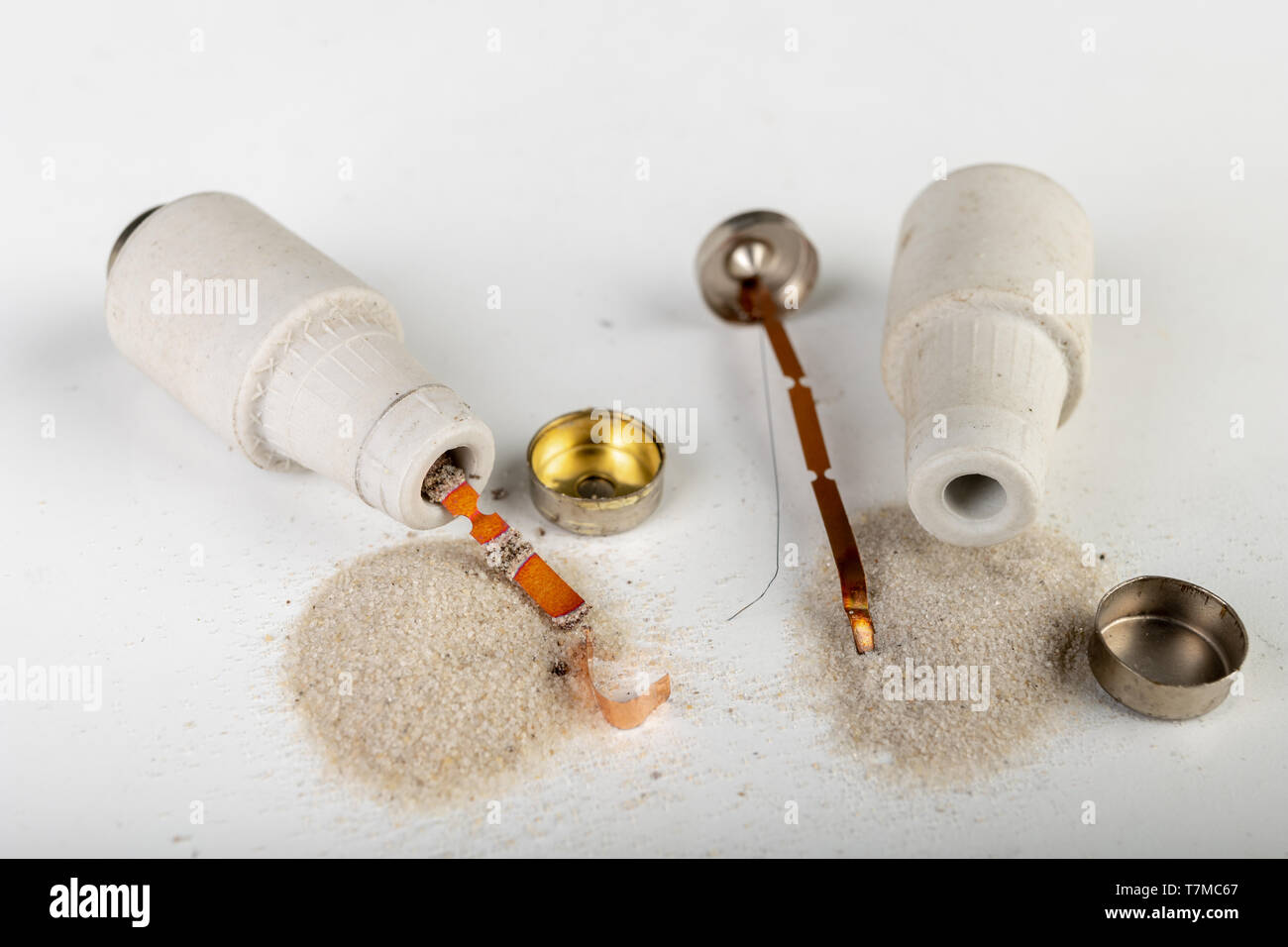 Old ceramic electric fuse. Blown and badly repaired security for energy, Bright background Stock