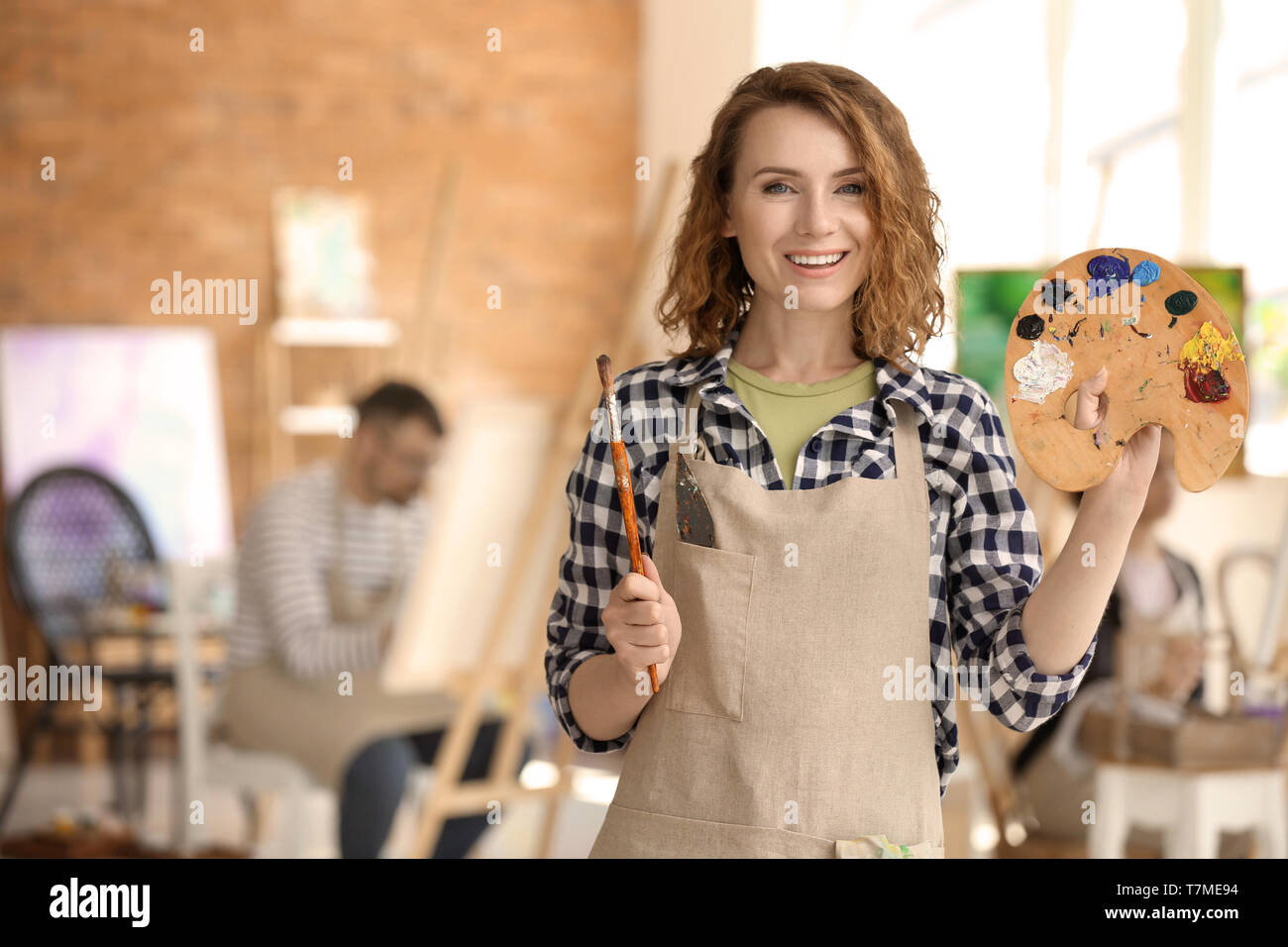 Female artist with brush and paint palette in workshop Stock Photo - Alamy