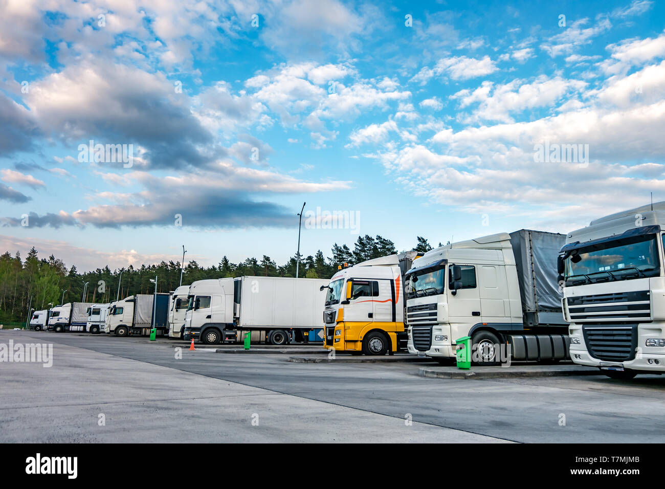 Trucks in a row with containers in the parking lot near forest
