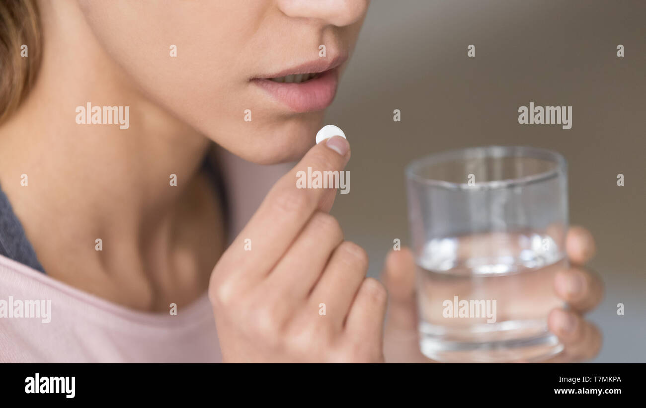 Close up image woman holding pill and glass of water Stock Photo