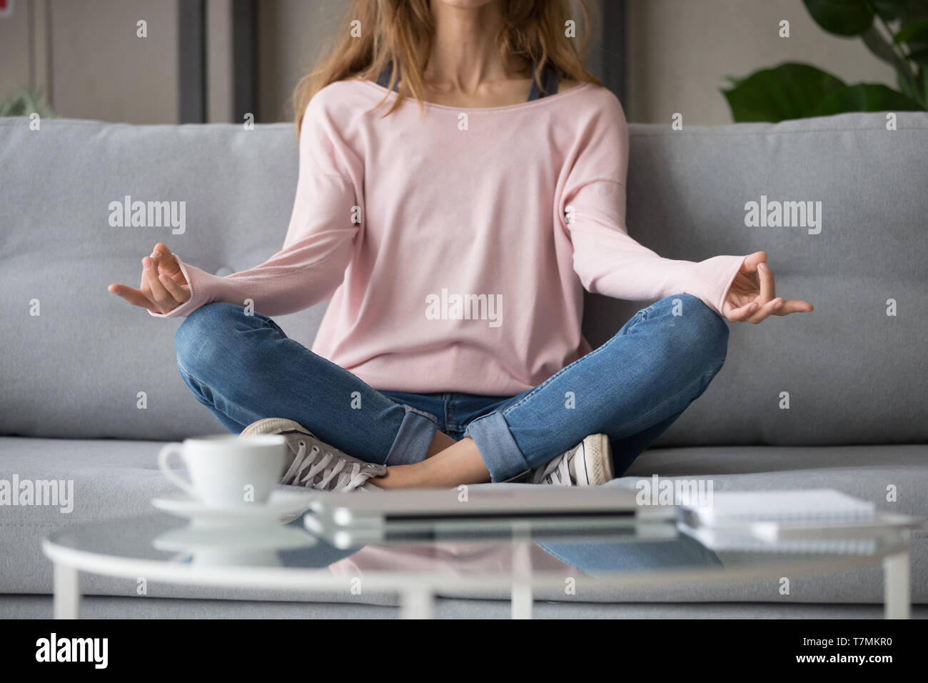 Cropped image woman sitting on couch in lotus pose meditating Stock ...
