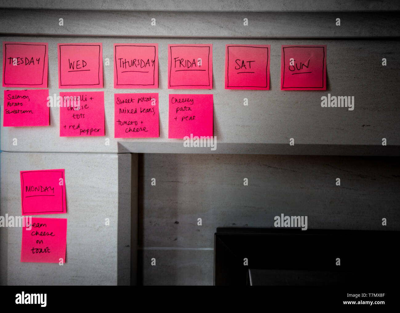 A bright abstract image of a meal list and days of the week on pink sticky notes Stock Photo