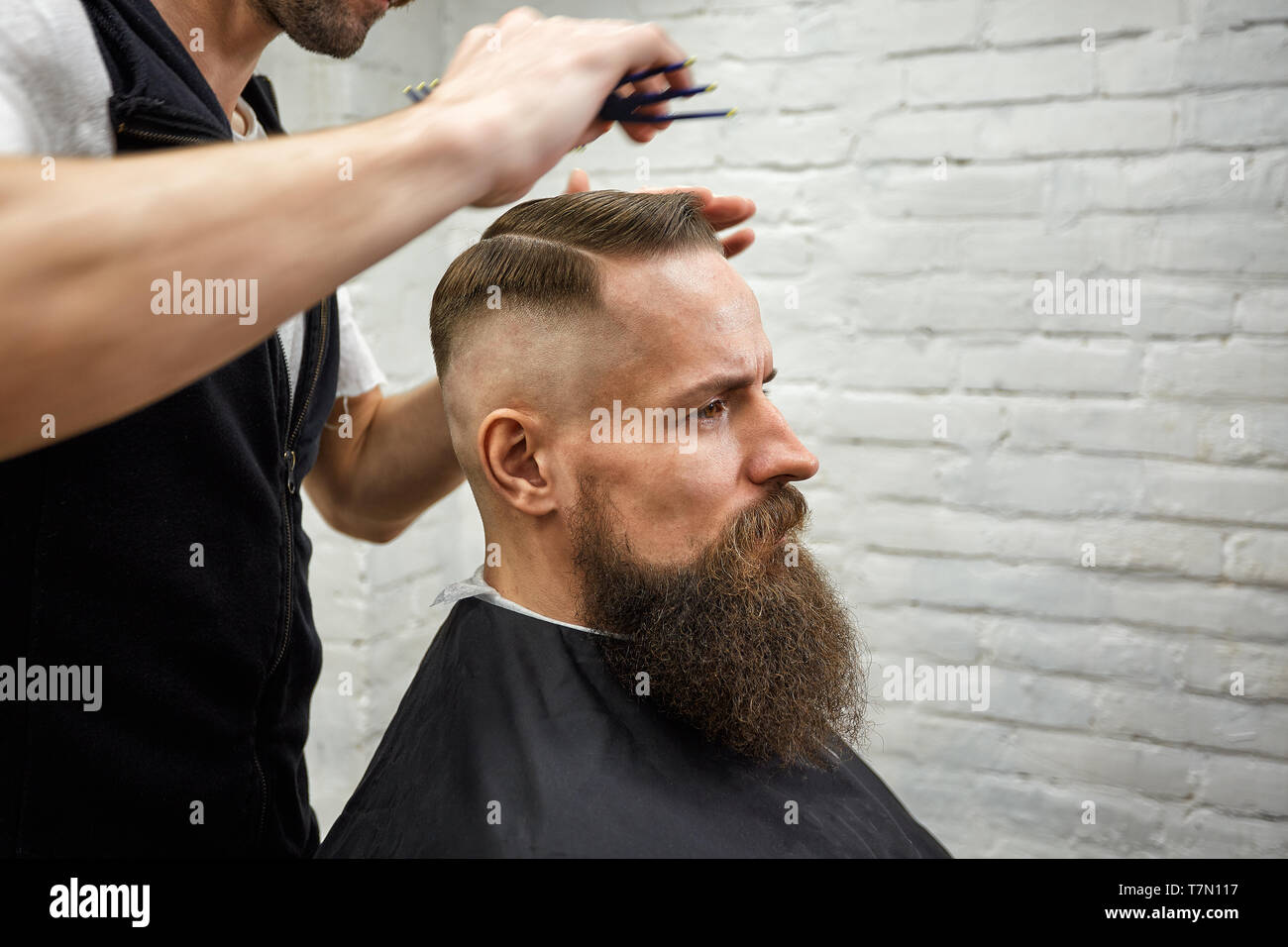 Master cuts hair and beard of men in the barbershop, hairdresser makes  hairstyle for a young man Stock Photo - Alamy