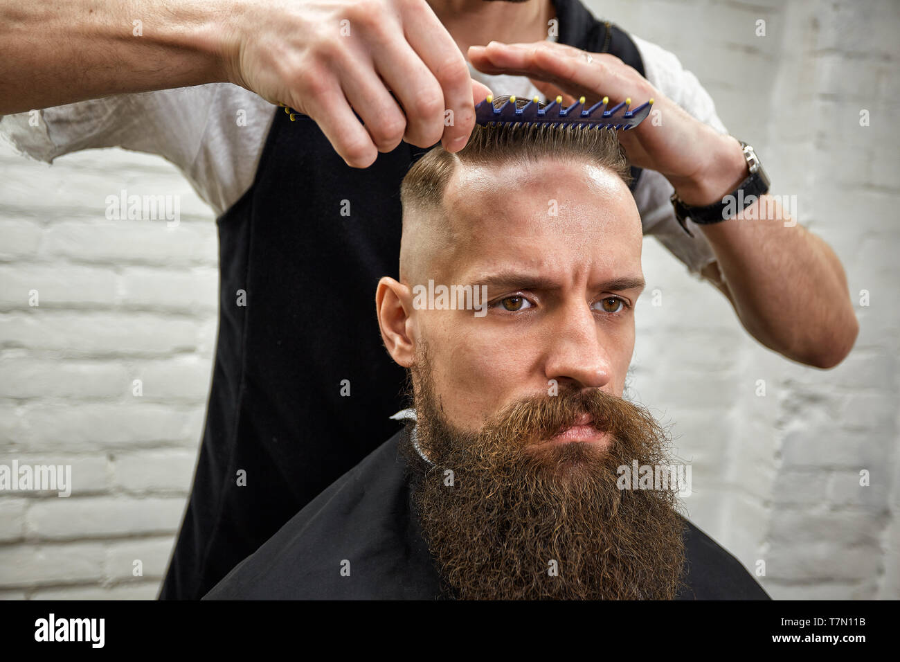 Master cuts hair and beard of men in the barbershop, hairdresser makes  hairstyle for a young man Stock Photo - Alamy