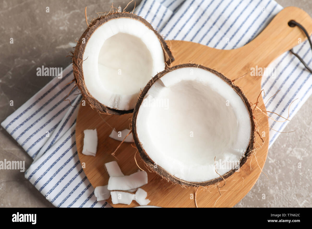 Cutting board with split coconut on table, space for text Stock Photo