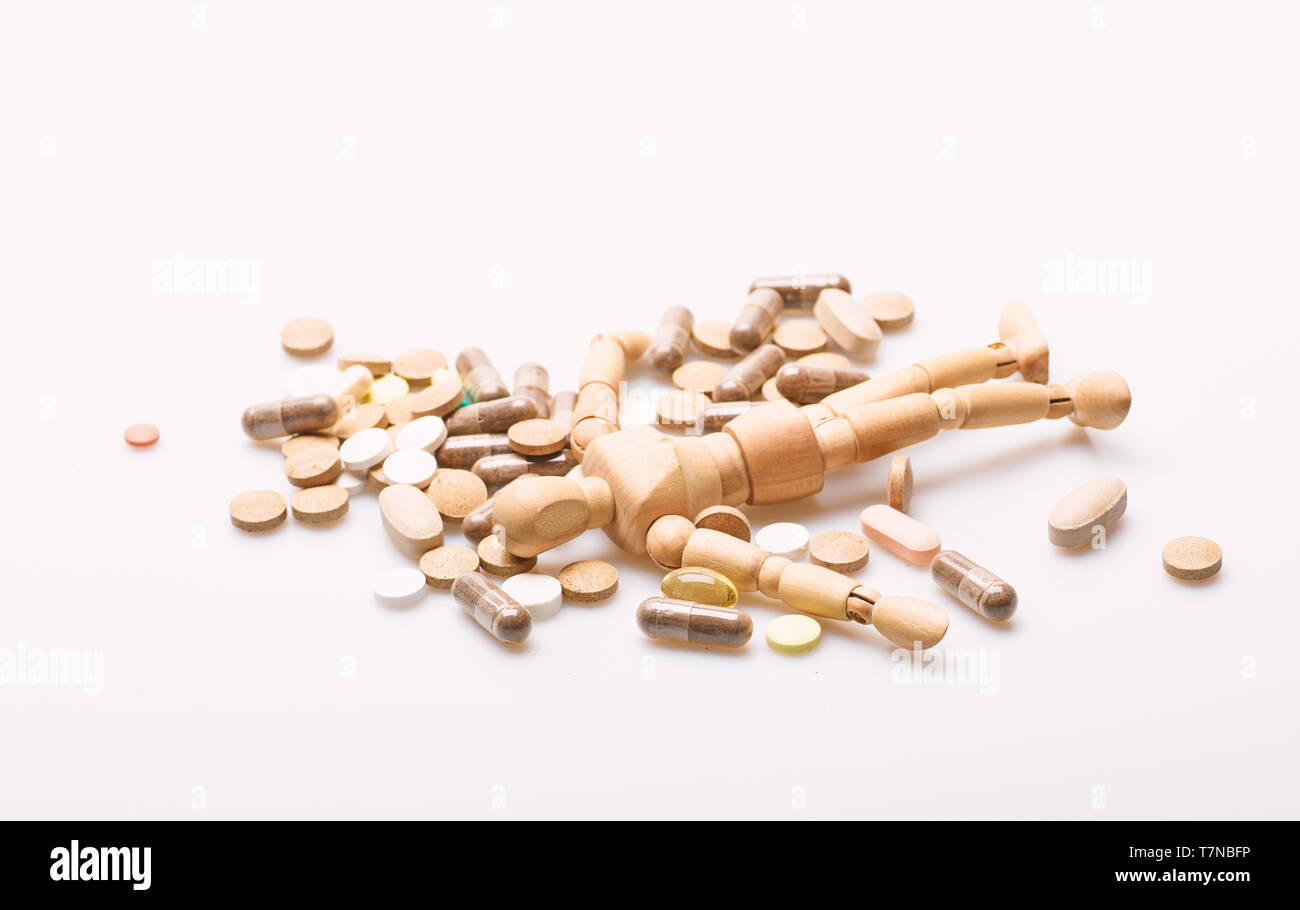 Wooden human dummy lay on pile of pills and tablets. Take medicine