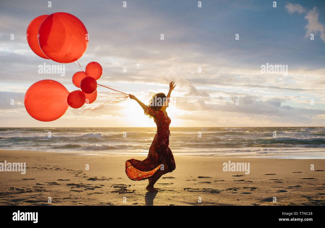 Young beautiful woman running on the beach holding balloons. Woman with  balloons on the beach enjoying a summer day Stock Photo - Alamy