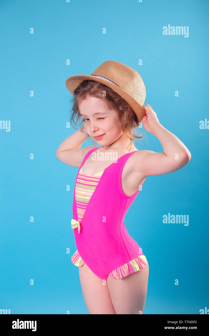 Cute little girl in swimsuit and hat smiling at camera on blue ...