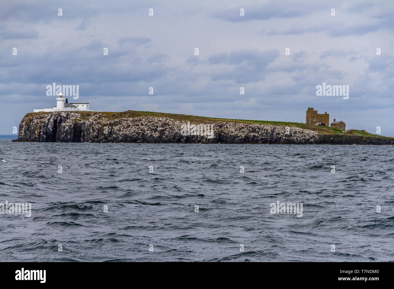 Farne Lighthouse built in 1811 on Inner Farne, with Brownsman island and beacon tower beyond. Farne Islands, Northumberland, UK. May 2018. Stock Photo
