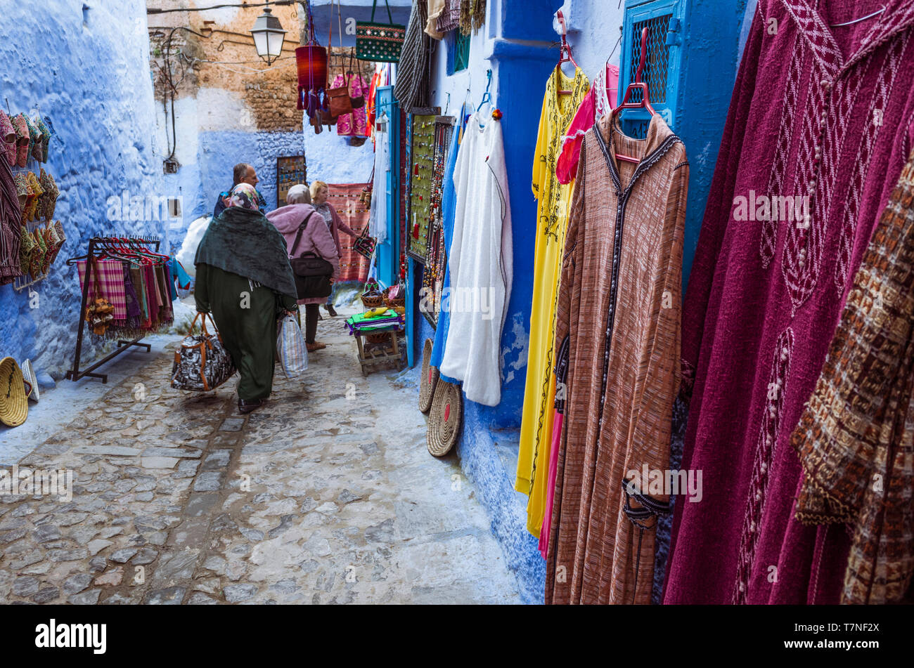 Chefchaouen, Morocco Two women walk past traditional clothing stores