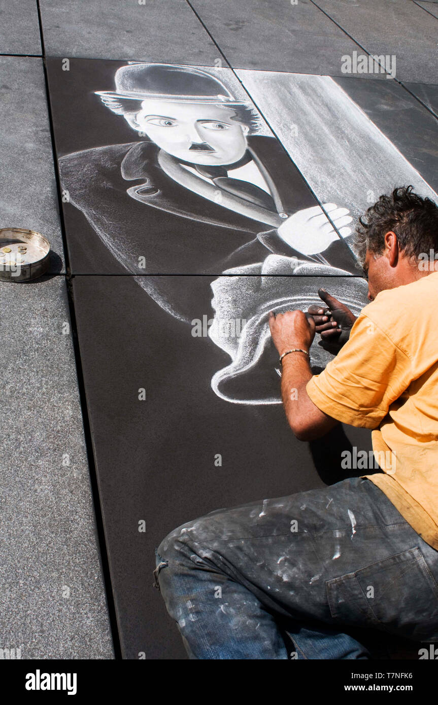 On the sidewalks of the Centre George Pompidou, a street artist draws an image of Charlie Chaplin as the little tramp from the silent movie 'The Kid'. Stock Photo