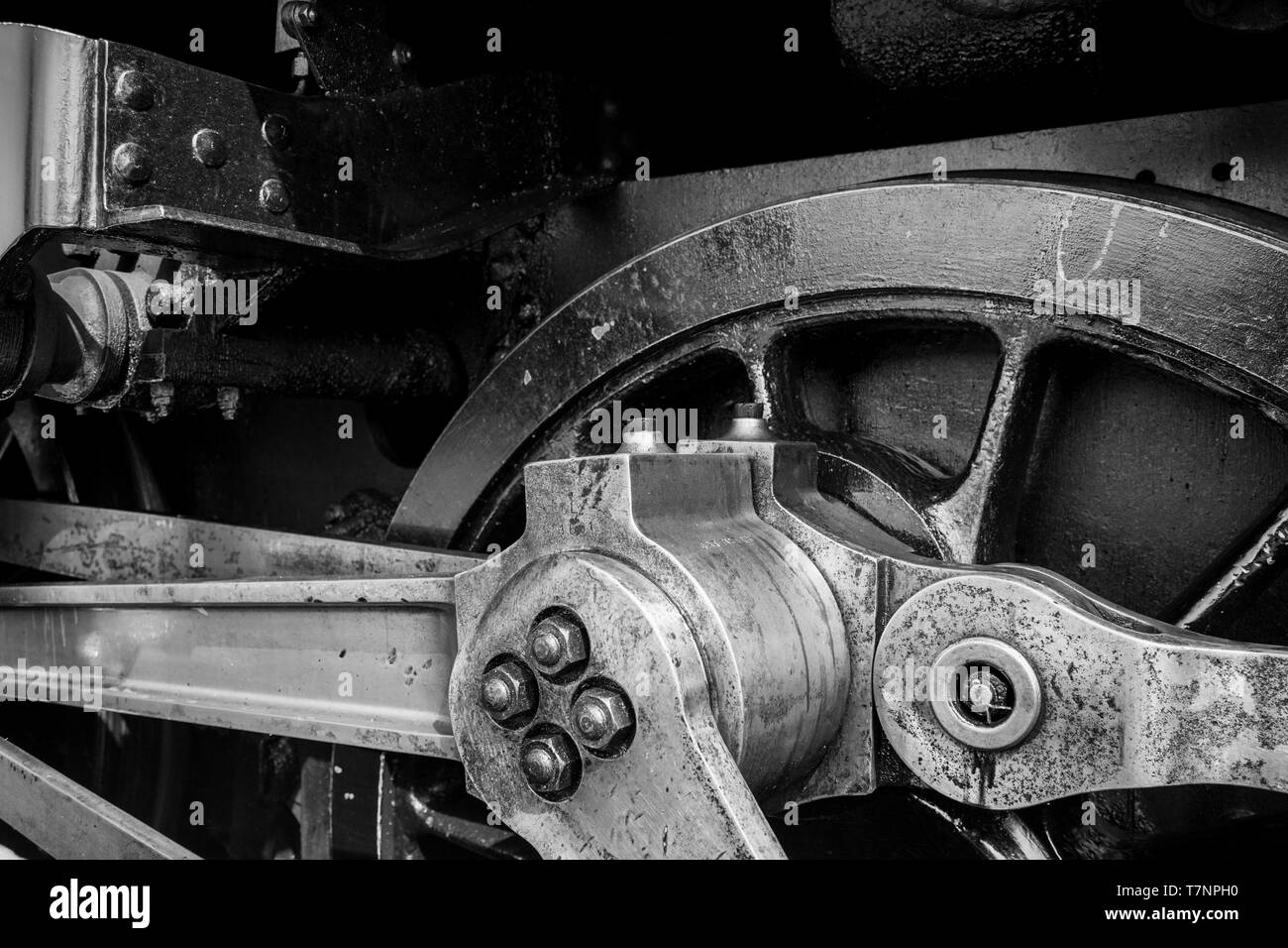 Monochrome close up of vintage UK steam locomotive driving wheel mechanism. UK steam engine connecting rod; UK steam trains; Heritage railway. Stock Photo