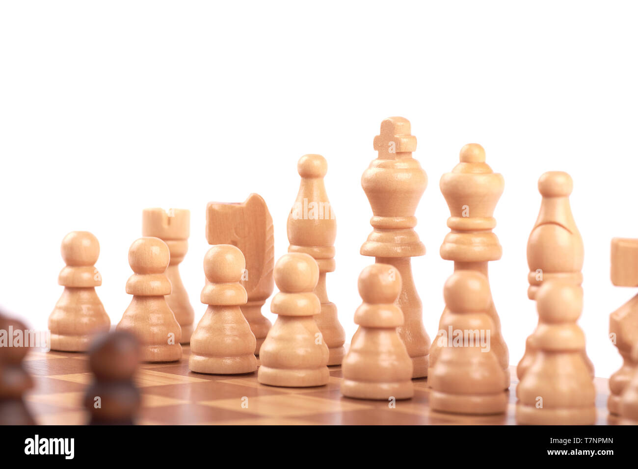 Set of white and black wooden chess pieces standing in a row on a chessboard, isolated on white background Stock Photo
