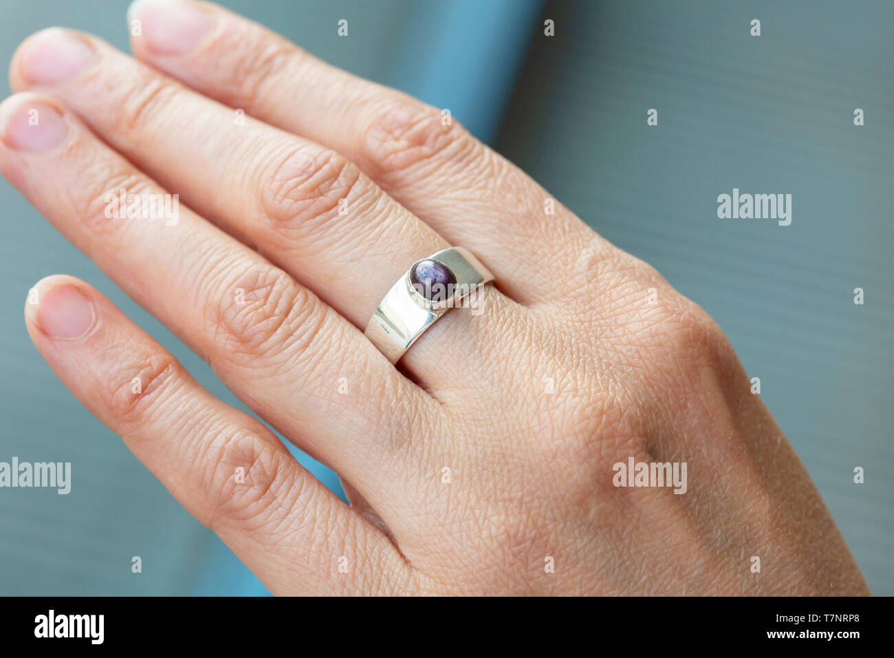 Female hand wearing silver ring with ruby star gemstone Stock Photo