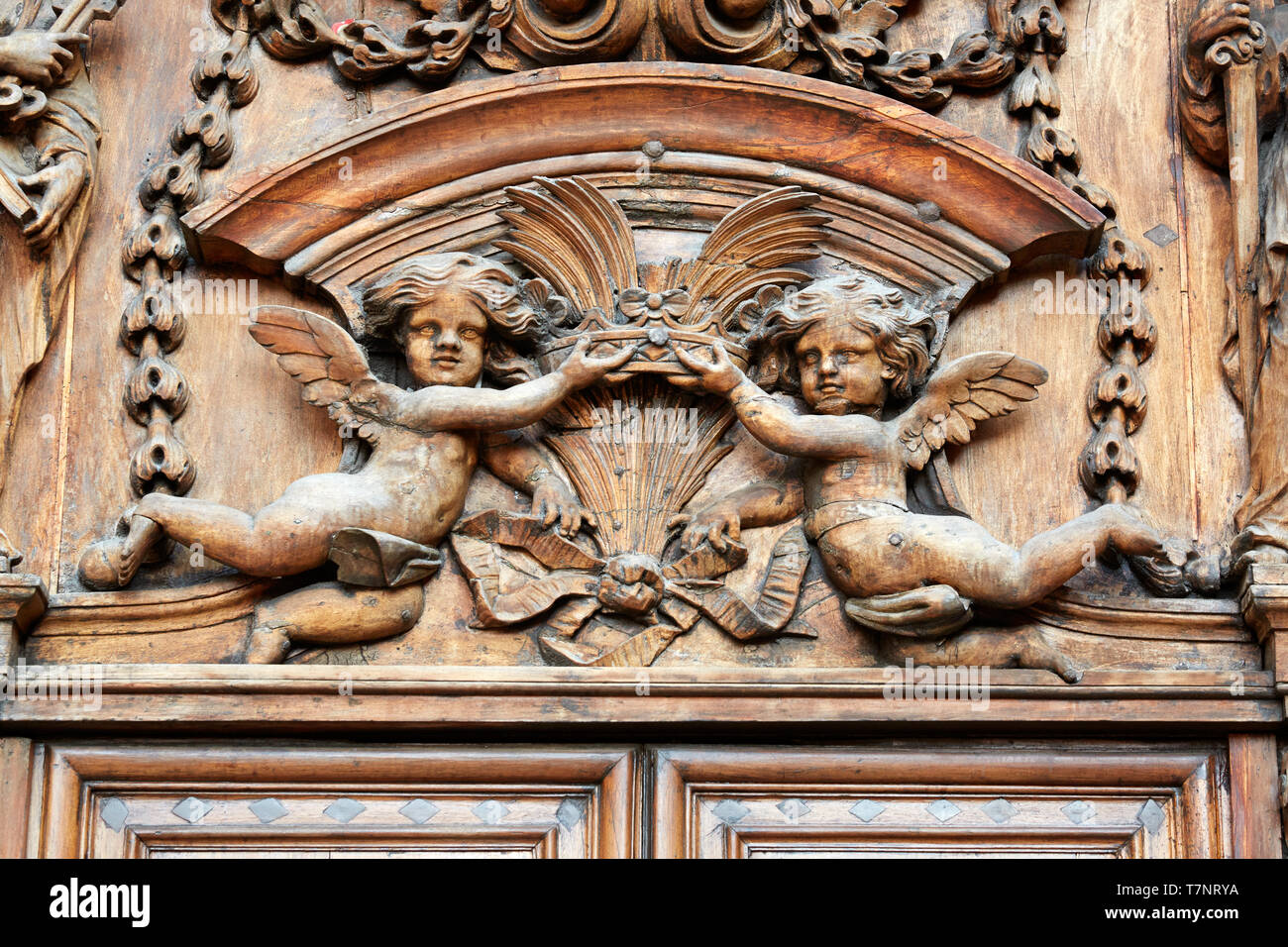 Ancient wooden portal with angels sculptures detail in Italy Stock Photo