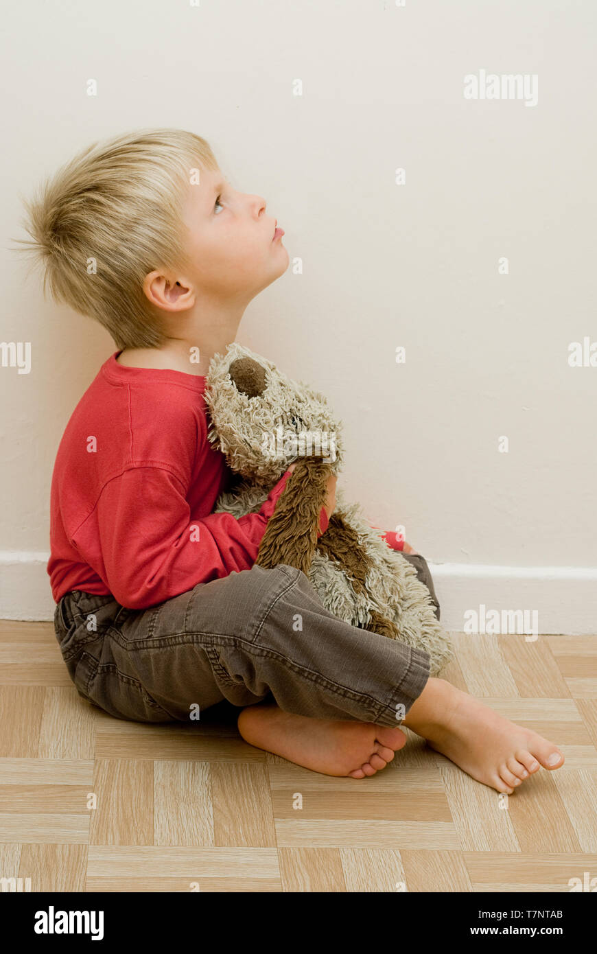 angry child looks upwards holding his toy dog. Stock Photo