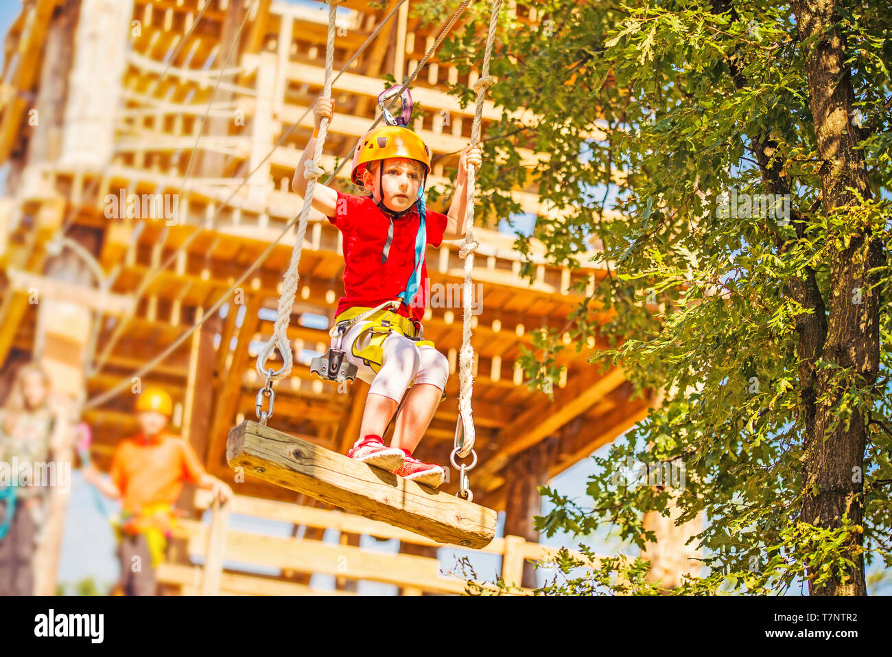 Little caucasian girl using a zip line in a rope playground structure