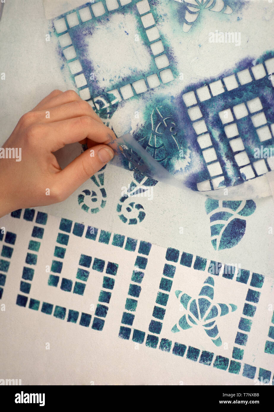 Hand removing stencil from tileeffect wall Stock Photo Alamy