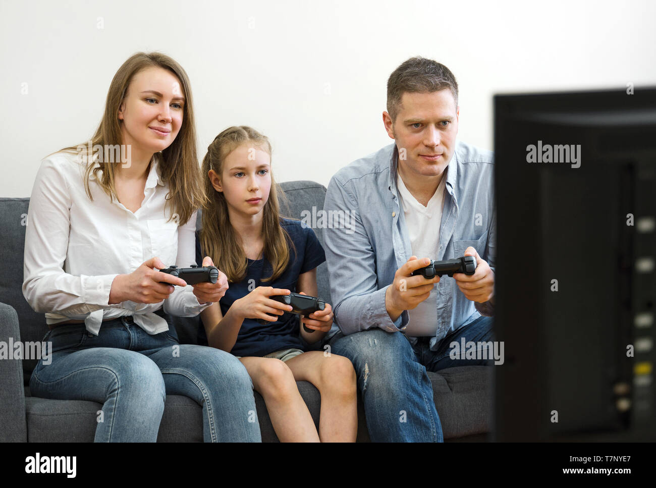 Mom, Dad and their daughter playing video game at home Stock Photo image picture