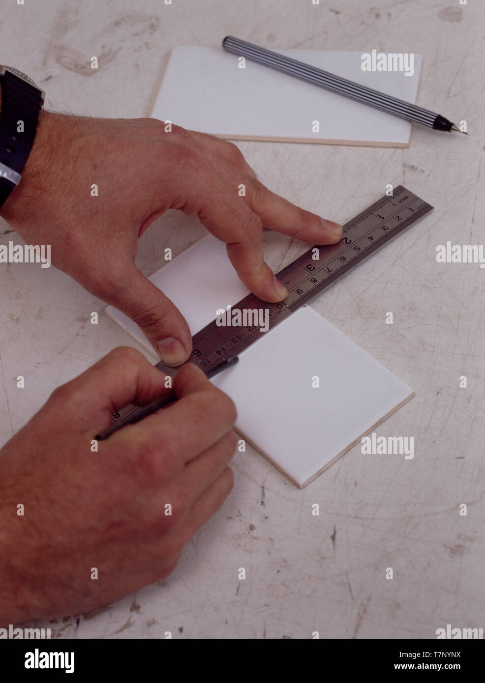 Hands measuring tiles with ruler Stock Photo