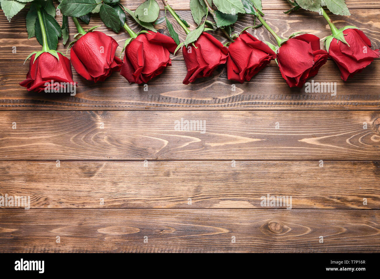 Beautiful red roses on wooden background Stock Photo - Alamy