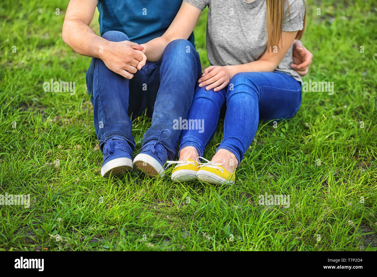 Happy young couple sitting on green lawn in park Stock Photo - Alamy