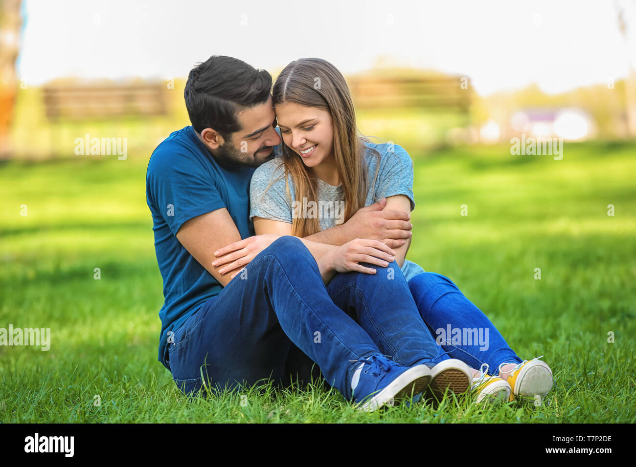 Happy young couple sitting on green lawn in park Stock Photo - Alamy